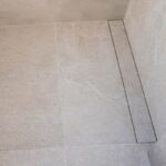 Sistema de desagüe oculto bajo pieza cerámica, diseñado para duchas con pendientes a 1, 2 o 4 direcciones.
